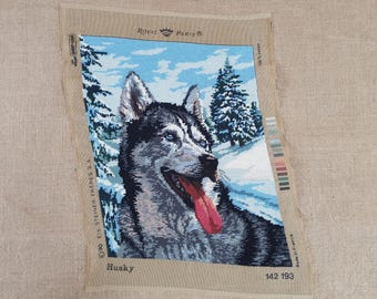 May include: A needlepoint canvas featuring a husky dog with blue eyes and a pink tongue. The canvas is titled "Husky" and has the Royal Paris logo in the top left corner.