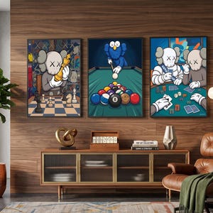 May include: Three framed wall art prints featuring cartoon characters with X-shaped eyes. The left print shows a character playing chess, the center print shows a blue character playing billiards, and the right print shows two characters playing cards.