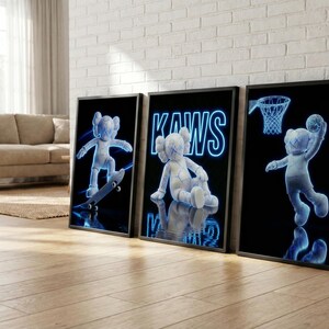 May include: Three framed art prints featuring a blue and white cartoon figure in various poses. One print shows the figure on a skateboard, another with the word "KAWS", and the third with the figure playing basketball. The background is black.