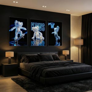 May include: Three framed art prints featuring a blue and white cartoon figure in various poses against a black background. The middle print displays the word "KAWS". The bedroom has a black bed, nightstands, lamps, and a dark rug.