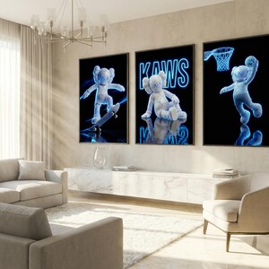 May include: Three framed art prints featuring a blue-toned KAWS character in different poses against a black background. One print shows the character skateboarding, another sitting, and the last one dunking a basketball. The word "KAWS" is in blue neon.