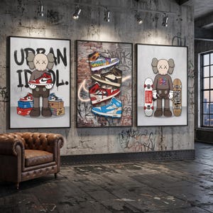 May include: Three framed wall art prints featuring cartoon figures and sneakers. The left print shows a character with X-eyes holding a red and white sneaker. The center print displays four stacked sneakers on a brick wall. The right print shows a character with two skateboards.