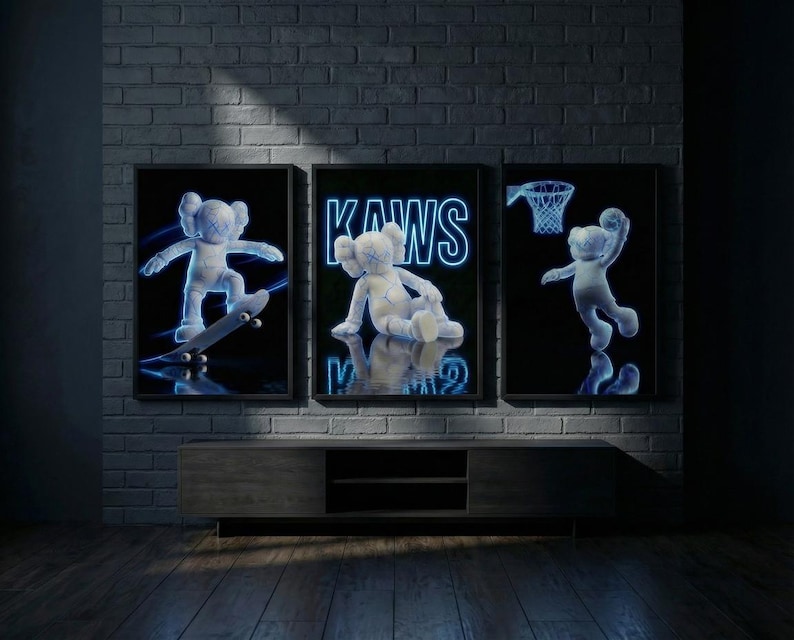 May include: Three framed art prints featuring a cartoon character in neon blue. One print shows the character skateboarding, another shows the word "KAWS", and the third shows the character playing basketball. The prints are displayed above a wooden cabinet.