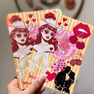 Puede incluir: Dos tarjetas decorativas con un fondo a rayas amarillas y blancas. Cada tarjeta presenta una ilustración retro de una mujer con sombrero de vaquero y gafas de sol en forma de corazón. Otras ilustraciones incluyen corazones, cerezas, dados y una pareja.