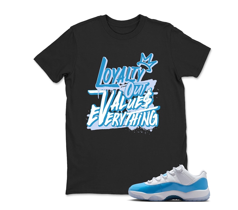 Puede incluir: Camiseta negra con el texto "Loyalty Out Values Everything" en azul claro y blanco. Un par de zapatillas blancas y azul claro est&aacute; al lado de la camiseta.