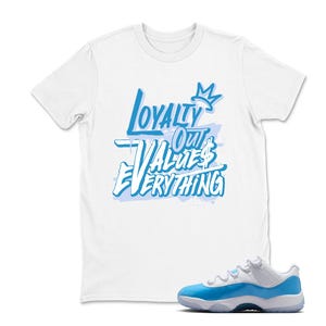 Puede incluir: Camiseta blanca con el texto "Loyalty Out Values Everything" en azul claro. Un par de zapatillas deportivas azules claras y blancas se encuentra en la esquina inferior derecha. Las zapatillas tienen una parte superior blanca y una suela azul claro.