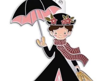 May include: A metal enamel keychain featuring a character wearing a black coat, a pink skirt, and a matching scarf. The figure holds a black umbrella with pink lining and carries a tan bag with floral details. A silver lobster clasp is attached at the top.