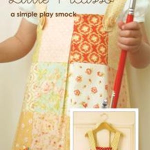 May include: A patchwork play smock with the text "Little Picasso" and "a simple play smock". The smock features various floral and geometric patterns in orange, yellow, and green. A pocket holds colored pencils. The image also shows a smaller version of the smock.