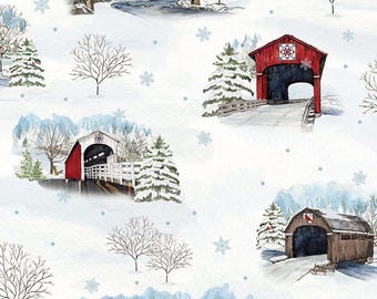 May include: A white fabric featuring a repeating winter pattern of red and brown covered bridges, snow-covered evergreen trees, bare winter branches, and blue snowflakes. A ruler at the bottom shows a scale of 12 inches for the fabric design.