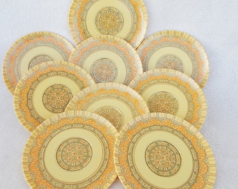 May include: A collection of nine decorative plates. Each plate features a central design with a yellow background, surrounded by concentric circles in orange, gray, and yellow. The plates have a scalloped edge.