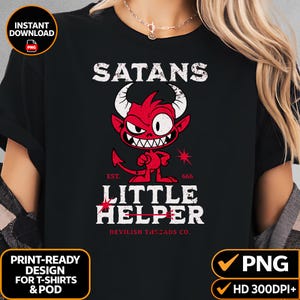 May include: A black t-shirt featuring a graphic of a red cartoon devil with horns and a tail. The text reads SATANS LITTLE HELPER, EST. 666, and DEVILISH THREADS CO. The design includes a small red star and a trident symbol integrated into the text.