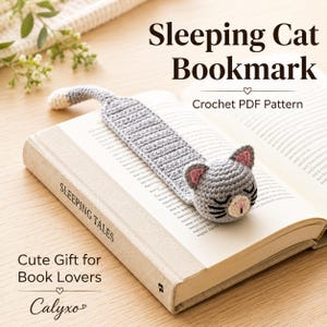 May include: A gray crocheted cat bookmark with a long body, a rounded head featuring pink inner ears and a pink nose, and a white-tipped tail. The bookmark rests on an open book titled Sleeping Tales, with text reading Sleeping Cat Bookmark.