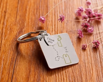 May include: A silver keychain with a white square tag and a small heart-shaped tag. The square tag has a map design with two green illustrations and the initials "P+K". The heart tag says "I love you".