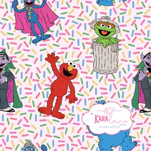 May include: A repeating pattern featuring Sesame Street characters including Elmo, Grover, Oscar the Grouch, and Count von Count on a light pink background with colorful sprinkles. A logo for Kara Lane Corner is visible in the bottom right.