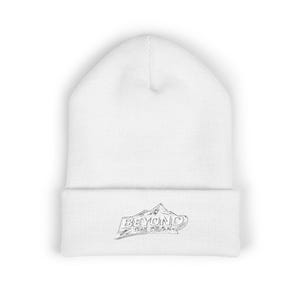 May include: White beanie hat with the text "BEYOND THE PEAK" in black. The hat has a mountain graphic. The beanie is made of a soft, knitted material.