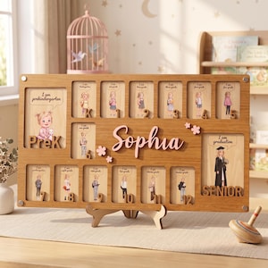 May include: A rectangular wooden school year photo board featuring the name Sophia in pink script. It includes slots for photos from PreK through 12th grade, each labeled with a cartoon illustration and grade level text, plus a graduation section.