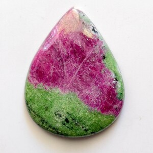 Peut inclure: Une pierre précieuse en forme de goutte d'eau aux couleurs vives. La pierre présente une combinaison saisissante de magenta profond, de vert clair et de nuances de rose. La surface polie révèle des motifs et des textures complexes.