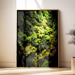 May include: A framed artwork featuring a close-up view of a vibrant green and yellow mossy landscape. The artwork is displayed in a room with natural light, next to a window and a decorative wooden side table.