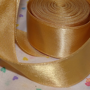 May include: A roll of gold satin ribbon. The ribbon is 2.5 cm wide and has a smooth, shiny finish.
