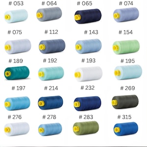 May include: A collection of twenty spools of sewing thread arranged in a grid, each featuring a bright yellow plastic core. The spools display a variety of colors including shades of blue, green, gray, and white, each labeled with a specific number.