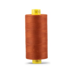 Puede incluir: Una bobina de hilo de coser naranja con una etiqueta amarilla que dice " Gütermann 100% Polyester 1093 715 1000 m "