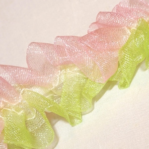 May include: Pink and green ruffled trim with a shimmery finish. The trim is made of a soft, sheer fabric and is perfect for adding a touch of elegance to any project.