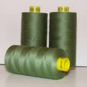 May include: Three spools of green thread with yellow labels. The labels have the text "100% COT 1000 000 1 64 P60" on them.