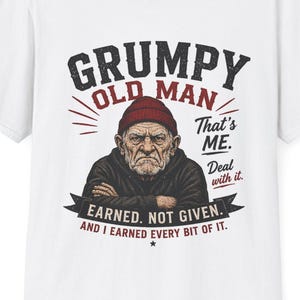 May include: White t-shirt featuring a graphic of a grumpy old man wearing a red beanie. The text reads "GRUMPY OLD MAN" above the illustration, with "That's ME. Deal with it." and "EARNED. NOT GIVEN. AND I EARNED EVERY BIT OF IT." below.