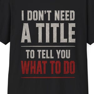 May include: Black t-shirt with the text "I DON'T NEED A TITLE TO TELL YOU WHAT TO DO" in white and red lettering. The shirt has a crew neck and short sleeves. The shirt is made of a soft material.