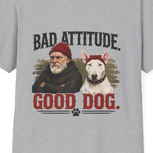 May include: A heather gray t-shirt with the words "BAD ATTITUDE. GOOD DOG." printed in black and red. The graphic features an illustration of a man and a dog, both wearing red hats.