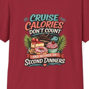 May include: A maroon t-shirt with a colorful graphic that reads "Cruise Calories Don't Count" and "And Neither Do Second Dinners." The graphic features illustrations of desserts like cake, a donut, and a cupcake. The shirt is a short-sleeved crew neck.