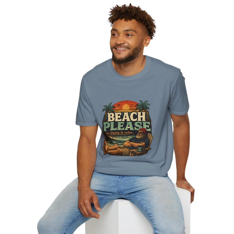 A smiling man wearing a t-shirt with a beach-themed graphic and text.