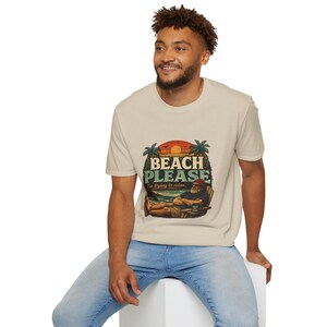 A smiling man wearing a t-shirt with a beach-themed graphic and text.