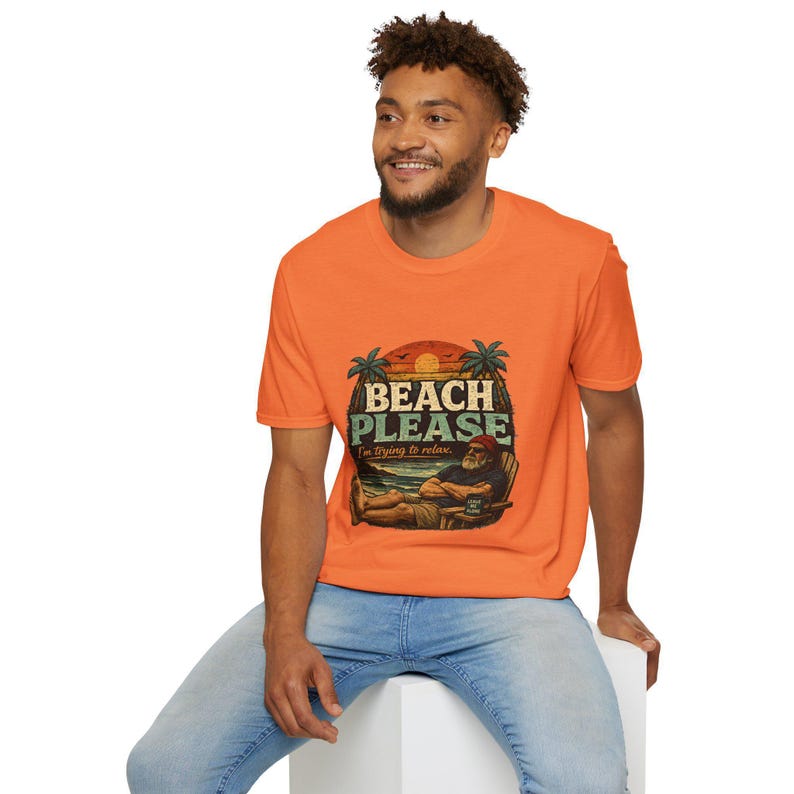 A smiling man wearing an orange t-shirt with a beach-themed graphic and text.