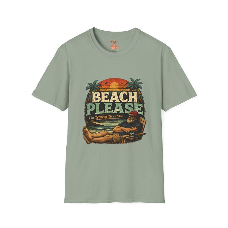 A t-shirt with a graphic design featuring a man relaxing on a beach, with the text "BEACH PLEASE I'M DYING TO RELAX" prominently displayed.