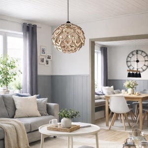 Könnte beinhalten: Dekorative, kugelförmige Pendelleuchte mit offenem Holzdesign. Die Leuchte hängt an einem schwarzen Kabel in einem Wohnzimmer mit grauem Sofa, weißen Wänden und blau-grauen Paneelen.