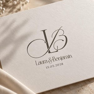 Puede incluir: Una tarjeta de color crema con un monograma gris oscuro de las letras L y B en una fuente serif estilizada. Debajo del monograma, el texto dice Laura & Benjamin seguido de la fecha 15.05.2028 en una tipografía limpia y elegante.
