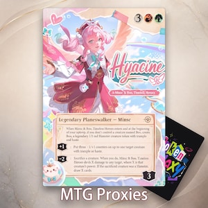 May include: A rectangular trading card featuring a pink-haired character in a red and white outfit with the text Hyacine, A-Minsc & Boo, Timeless Heroes. The card includes game rules, a mana cost of 3, and a loyalty value of 3, with a small hamster icon.