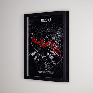 May include: A framed wall art print featuring a black map of the Suzuka circuit with a bold red track outline. The text reads SUZUKA, LOCATION: SUZUKA, JAPAN OPENED: 1962, TURNS: 18 LENGTH: 5.807 KM (3.608 MI) and includes a small Japanese flag icon.