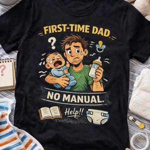 Pode incluir: Camiseta preta com uma ilustração humorística. O desenho mostra um pai de desenho animado estressado segurando um bebê chorando e uma mamadeira. O texto diz "FIRST-TIME DAD" e "NO MANUAL. Help!!" com ícones de bebê.
