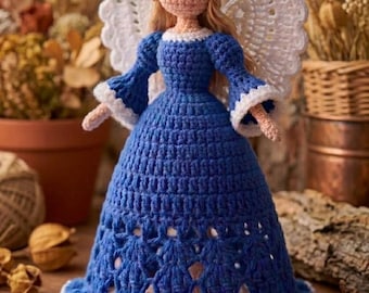 May include: A crocheted angel doll featuring a blue dress with a white ruffled hem and cuffs, white lacy wings, and a gold-coloured halo. The doll has light-coloured yarn hair and a textured, light-tan crocheted face without defined facial features.