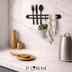 May include: A kitchen setting featuring a black utensil rack with a fork, knife, and spoon. A small metal bucket with greenery hangs beneath. A wooden spoon rests on a wooden plate. A wooden salt shaker and cup are also visible. The word "FORM" is at the bottom.
