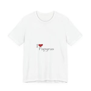 Puede incluir: Camiseta blanca con el texto "I ❤️ Papyrus" en negro y un símbolo de corazón rojo. La camiseta es de cuello redondo y parece estar hecha de un material suave.