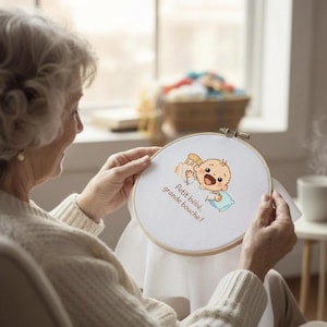 Peut inclure: Un cercle à broder avec un motif de bébé de dessin animé et le texte "Petit bébé, grande bouche!" en marron. Le bébé a la bouche ouverte et tient un oreiller bleu. Le cercle est tenu par une personne.