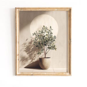 May include: A framed art print featuring a potted plant with green leaves and a brown stem. The plant sits in a beige pot against a beige background with a large, circular light source. The frame is a light, distressed wood.