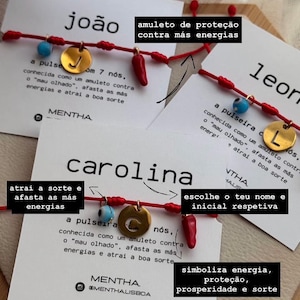 Può includere: Braccialetti con filo rosso con ciondoli dorati, perline blu e ciondoli a forma di peperoncino. Ogni braccialetto ha un nome e un'iniziale su una carta. Le carte hanno anche testo in portoghese.