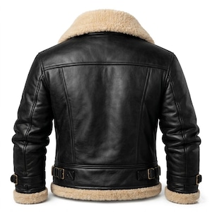 May include: A black leather jacket featuring a thick beige shearling collar and matching shearling trim at the cuffs and hem. The jacket includes adjustable side straps with metal buckles at the waist and additional buckle straps at the cuffs.