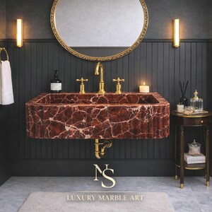 May include: A luxurious bathroom with a red marble sink and gold taps, a round gold mirror, and a small side table. The walls are dark grey, and the floor is marble. The text "LUXURY MARBLE ART" is at the bottom.