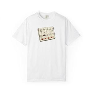 Puede incluir: Camiseta blanca con un gráfico de un sintetizador vintage. La ilustración del sintetizador es beige con detalles rojos, negros y blancos. La camiseta tiene cuello redondo y mangas cortas. La camiseta está hecha de un material suave y cómodo.