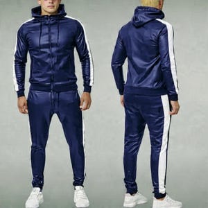 May include: Navy blue tracksuit with a hooded jacket and matching pants. The jacket has a zipper closure and white stripes down the sleeves. The pants also feature white stripes along the sides.